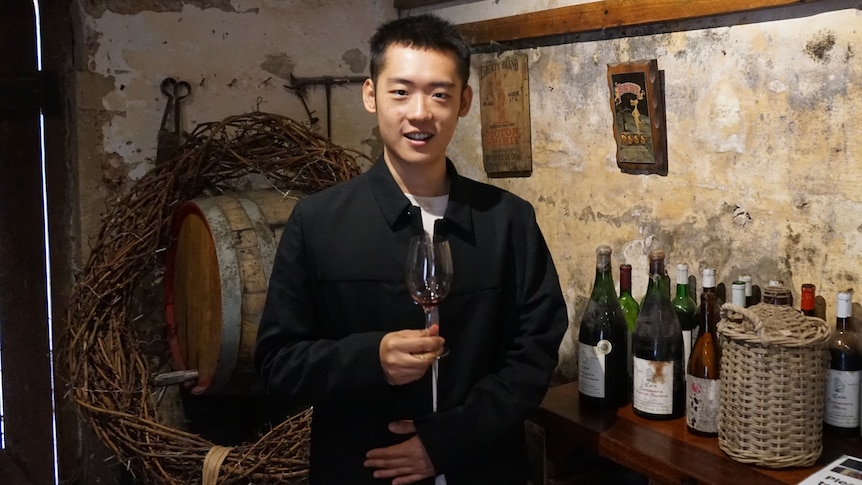 A man holds a wine glass at a winery.