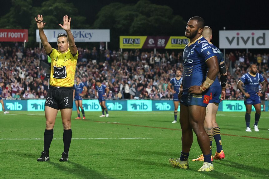 A ref holding his hands in the air, sending a payer to the sin-bin, who looks upset 