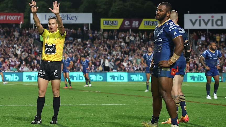 A ref holding his hands in the air, sending a payer to the sin-bin, who looks upset 