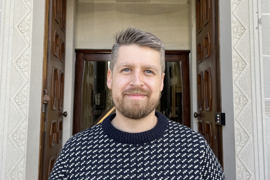 A bearded man looks at the camera.