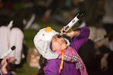 A young girl holds a telescope up to the sky.