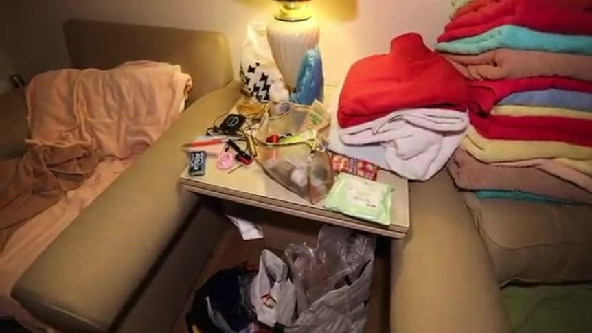 Room of illegal brothel shut down by ACT Policing, showing cleaning products, a condom, gloves and water bottle.
