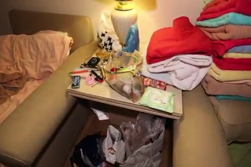 Room of illegal brothel shut down by ACT Policing, showing cleaning products, a condom, gloves and water bottle.