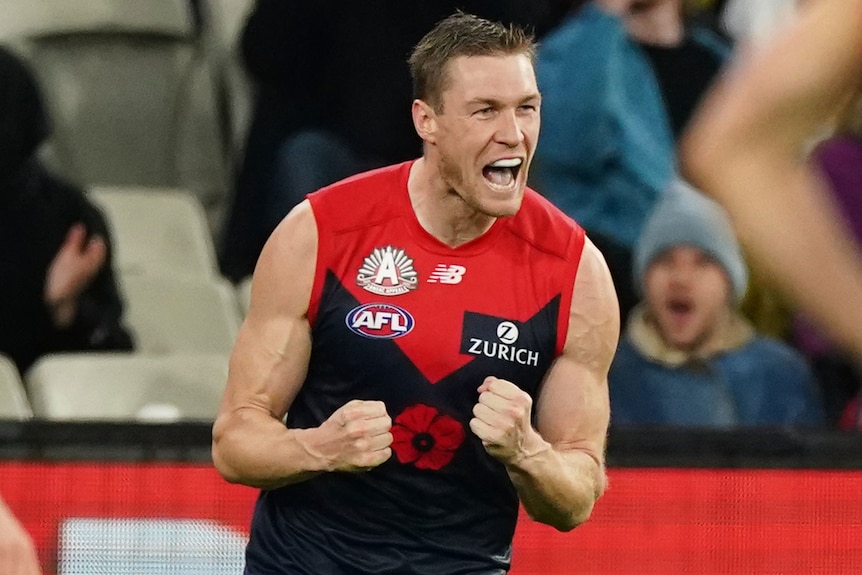 A Melbourne AFL player pumps both his fists as he celebrates a goal against Richmond.