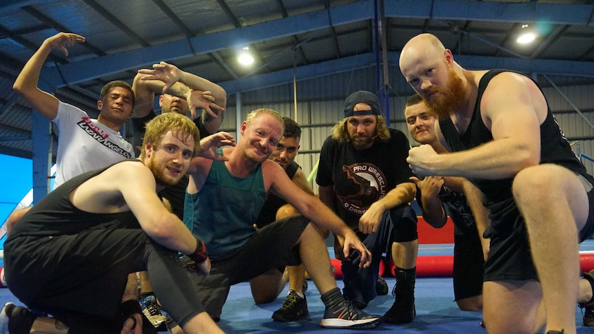 A group of Darwin wrestler squat and pose for the camera inside a gym