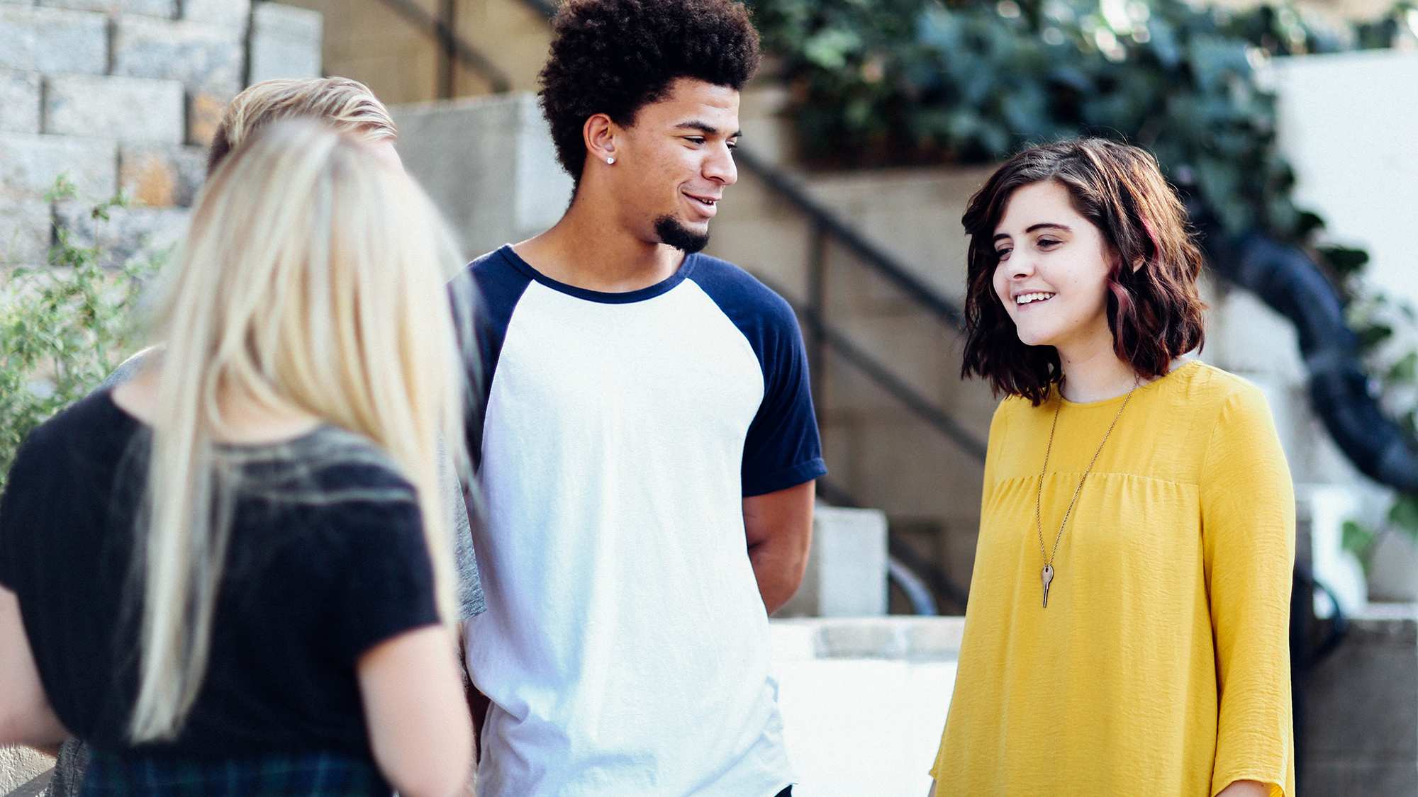 Four people have a conversation outside, depicting colleagues spending time together and boosting the mood at work.