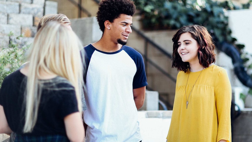 Four people have a conversation outside, depicting colleagues spending time together and boosting the mood at work.