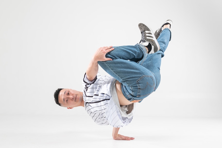 Dancer Jo Hyeon Yoon performing a breaking move, sideways with one hand on the ground and feet in the air.