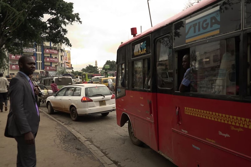 A red bus pulls up on a Nairobi street.