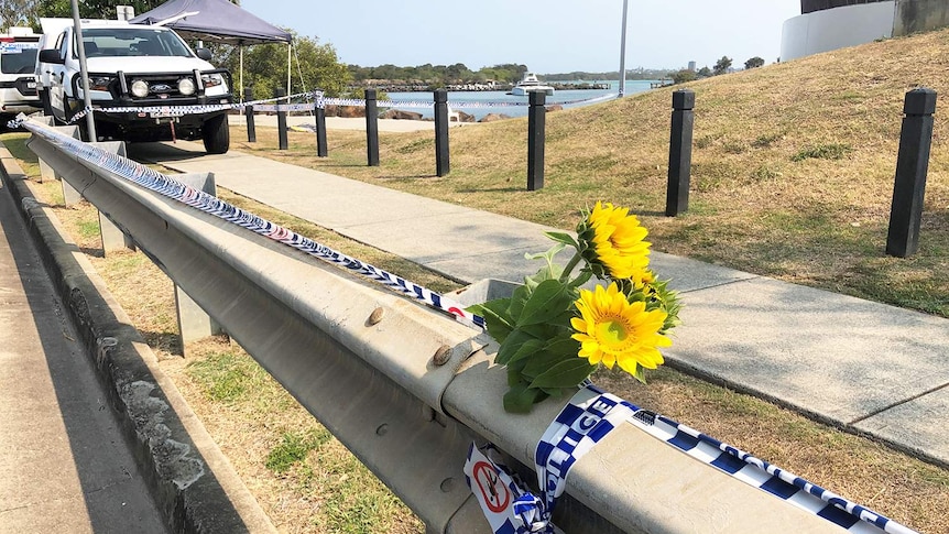 Flowers left at the scene and police vehicles where a body of a man was found.
