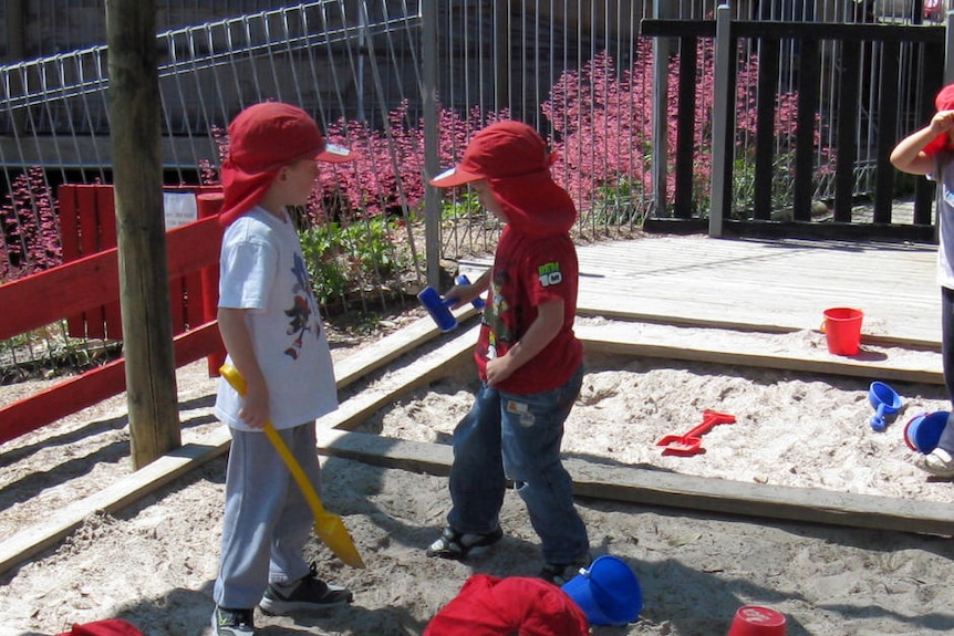 Children play in a sand pit at a childcare centre.