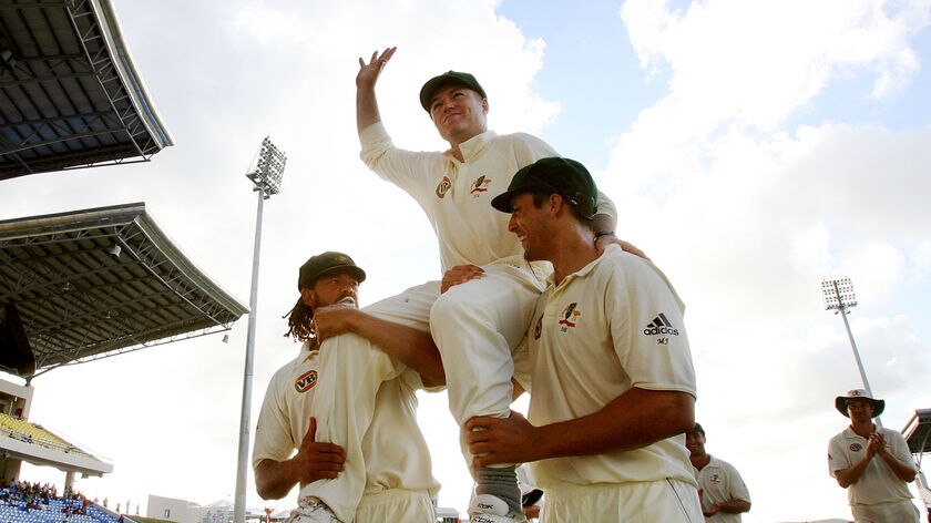 Australian bowler Stuart MacGill waves to the crowd as he is carried off