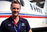 A man smiles at the camera in front of an RFDS plane. 
