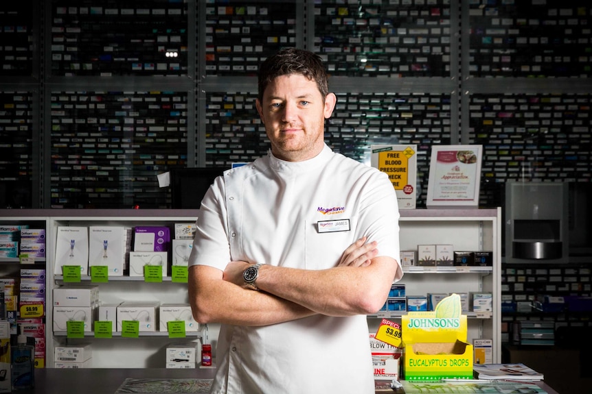 Pharmacist James Reid stands cross-armed in his pharmacy.