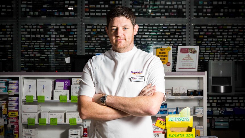 Pharmacist James Reid stands cross-armed in his pharmacy.