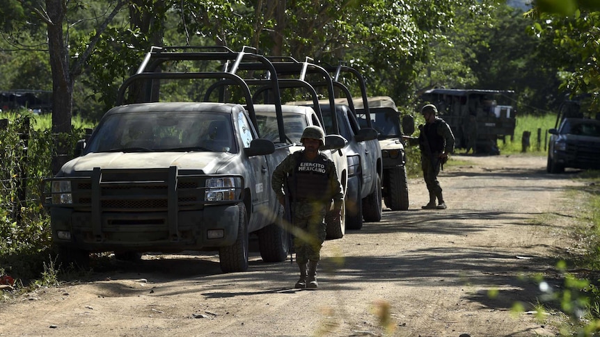 Mexican soldiers patrol the area where a military helicopter was shot down by cartel in response to antinarcotics operation.