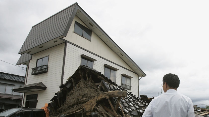 A man looks on at a collapsed house in northern Japan after an earthquake.