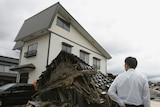 A man looks on at a collapsed house in northern Japan after an earthquake.