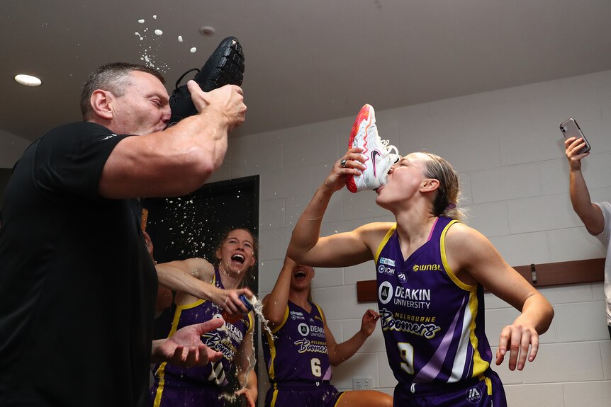 A man and a woman drink out of shoes, as a celebration for winning the WNBL Championship.