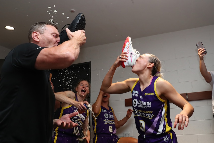 A man and a woman drink out of shoes, as a celebration for winning the WNBL Championship.