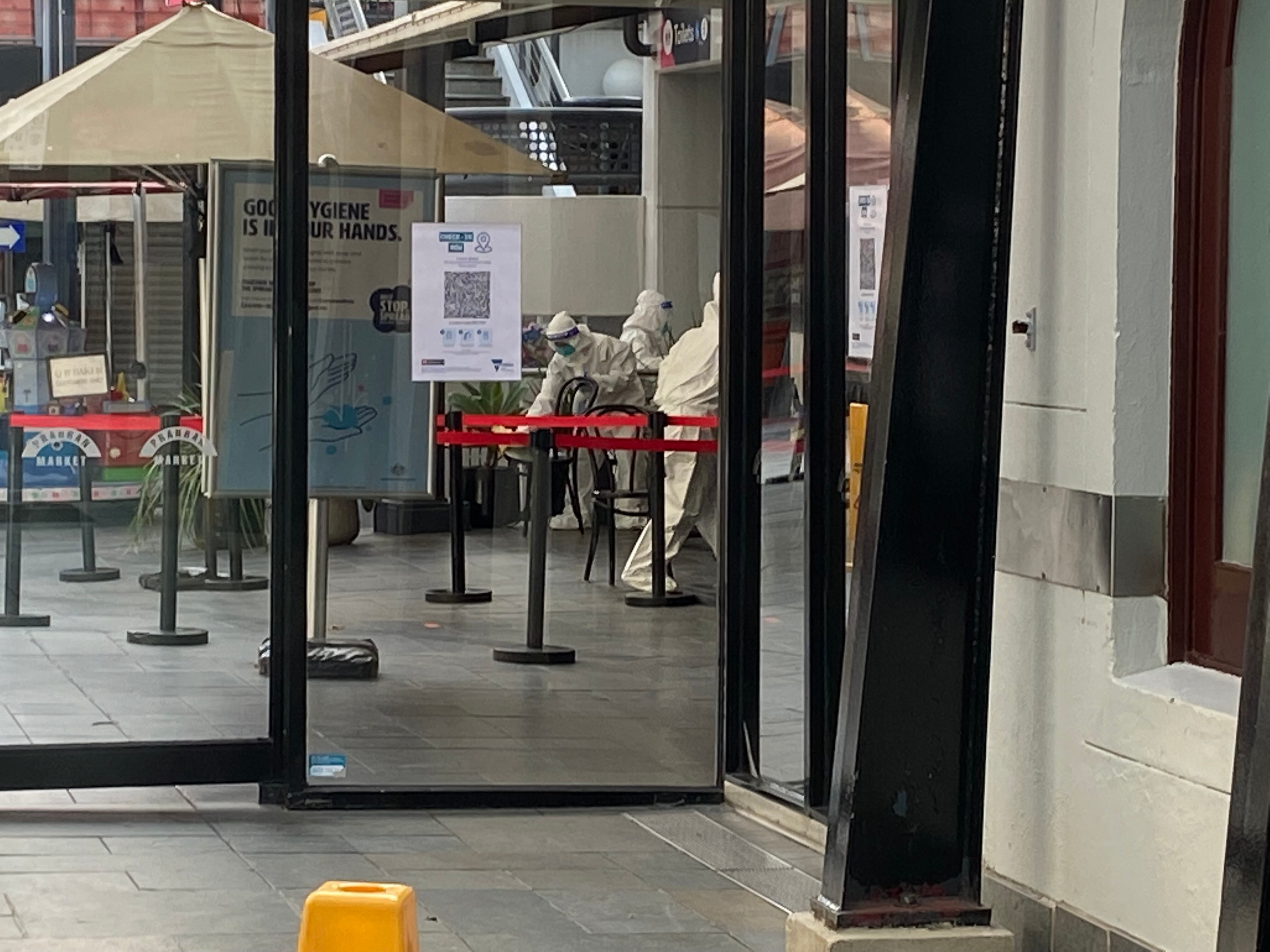 An individual dressed in protective gear cleaning inside a market.