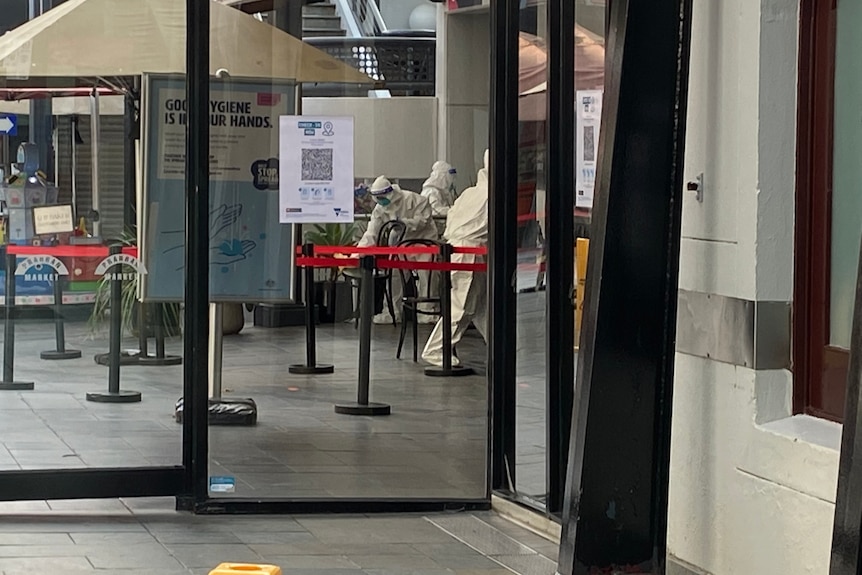 An individual dressed in protective gear cleaning inside a market.