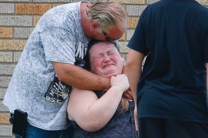 People hug and cry outside of the Santa Fe High School