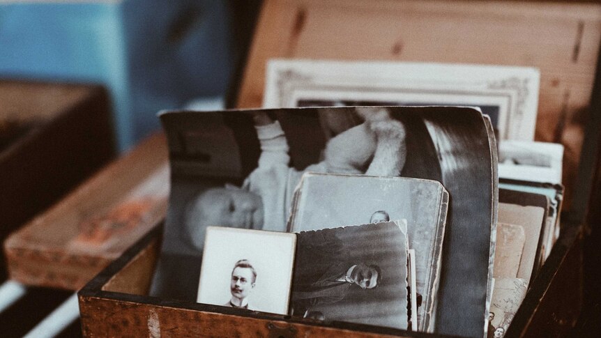 Wooden box filled with old black and white family photos.