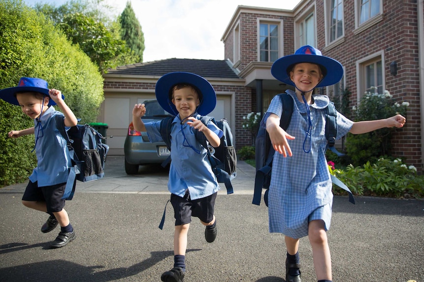 The triplets look excited in their school uniforms.