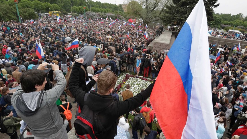 Crowds of people wave Russian flags at a rally in St Petersburg.