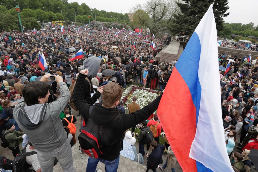 Crowds of people wave Russian flags at a rally in St Petersburg.