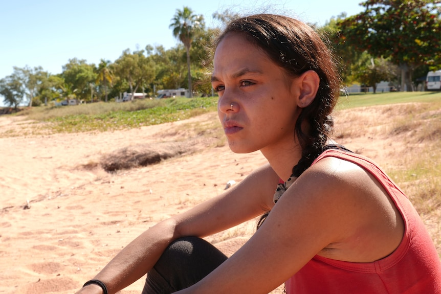 Caitlyn Roe sits on the beach and looks out into the distance.