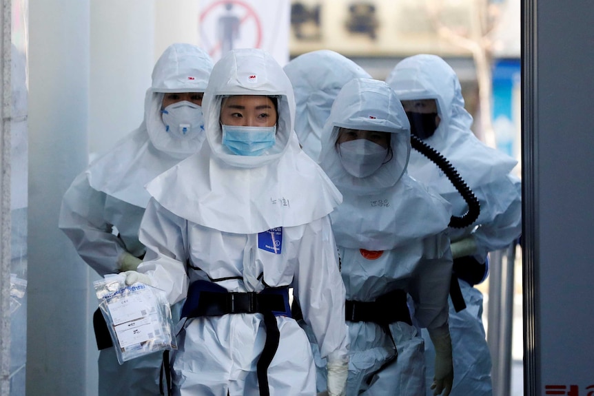 A group of medical workers at a hospital walk covered in protective gear as they treat coronavirus patients