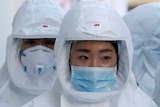 A group of medical workers at a hospital walk covered in protective gear as they treat coronavirus patients