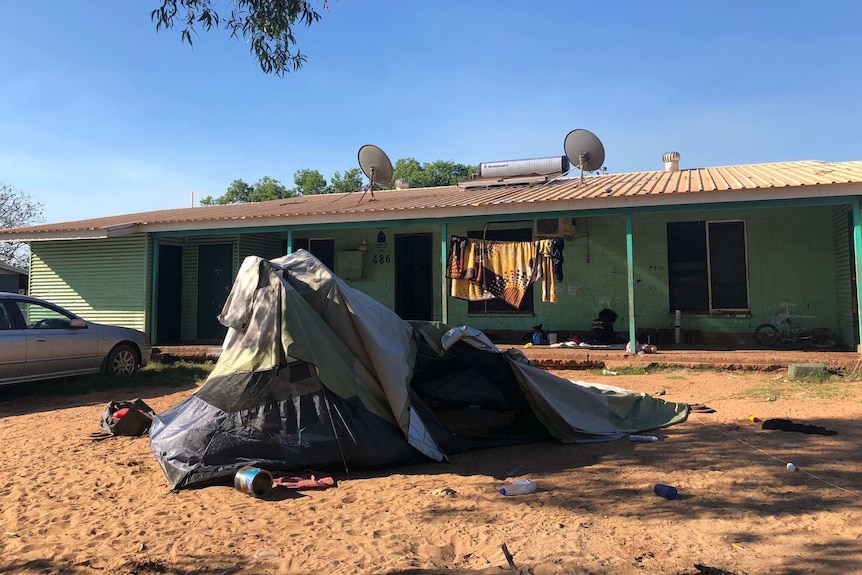 A green house with a collapsing tent in the front yard