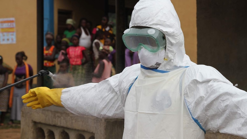 Ebola worker in white suit being sprayed with disinfectant