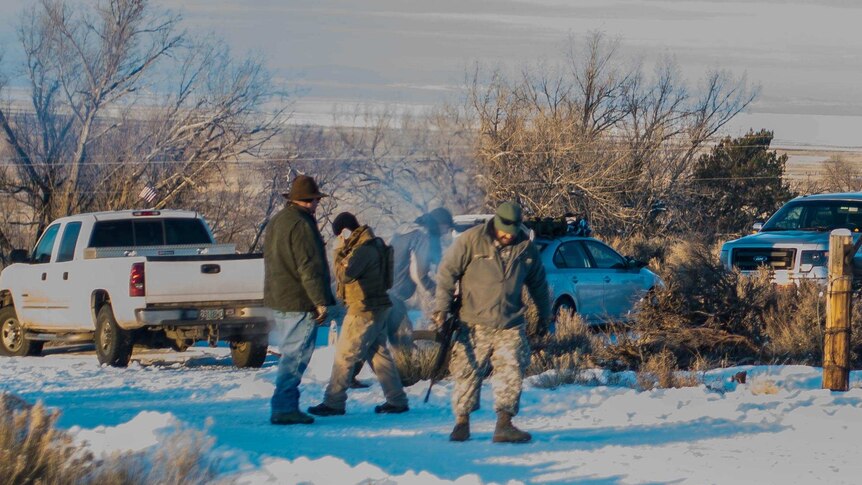 Armed militia, one holding a rifle by his side, walk through the snow in the Malheur Wildlife Refuge HQ in Oregon.
