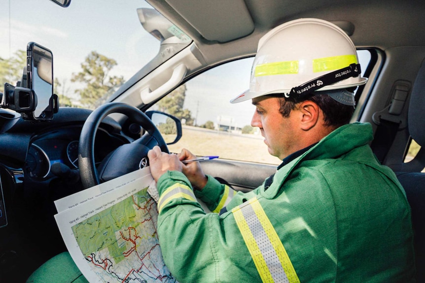 Andy Beckett sits in  his car and studies his map of the area the Forest Fire Management crew need to cover for the day.