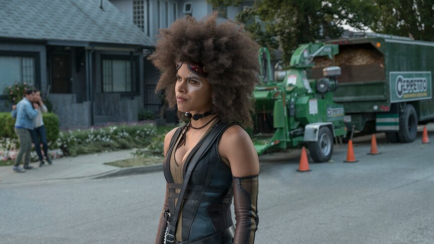 Colour photograph of actor Zazie Beetz as Domino standing in a suburban street in 2018 film Deadpool 2.