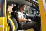 side view of vladimir putin wearing sunglasses fastens his seatbelt in the front seat of a yellow car