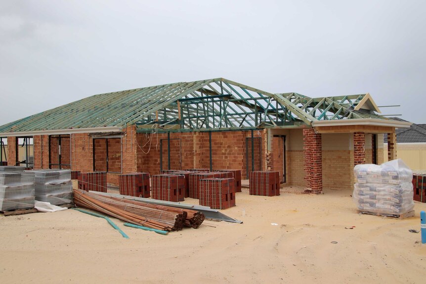 A house under construction with building materials in the foreground.
