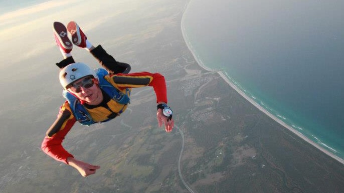 Ben Dummett sky diving over a shoreline.