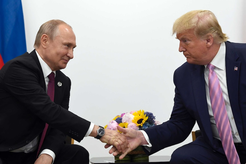 President Donald Trump, right, shakes hands with Russian President Vladimir Putin.
