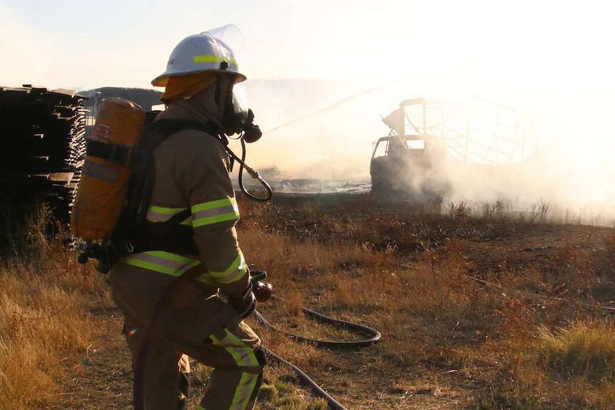Firefighters in burnt field with smoke.