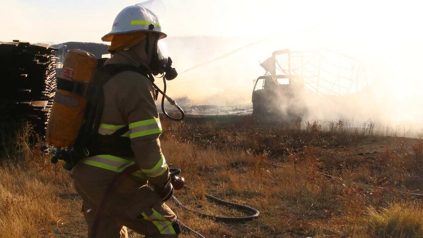Firefighters in burnt field with smoke.