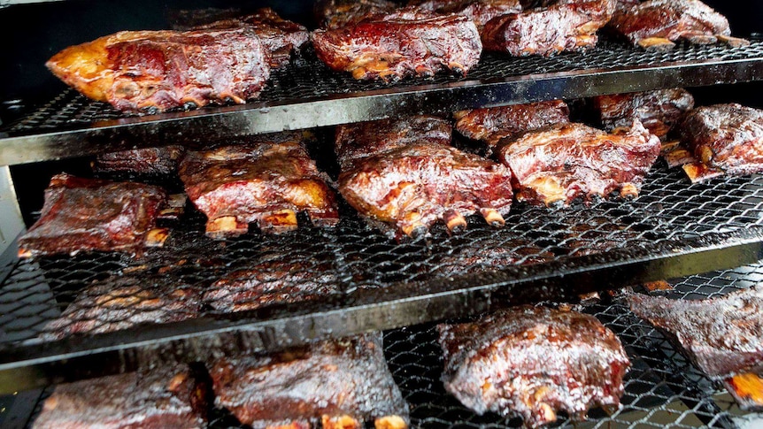 Beef ribs cooking on multiple grills.