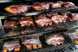 Beef ribs cooking on multiple grills.