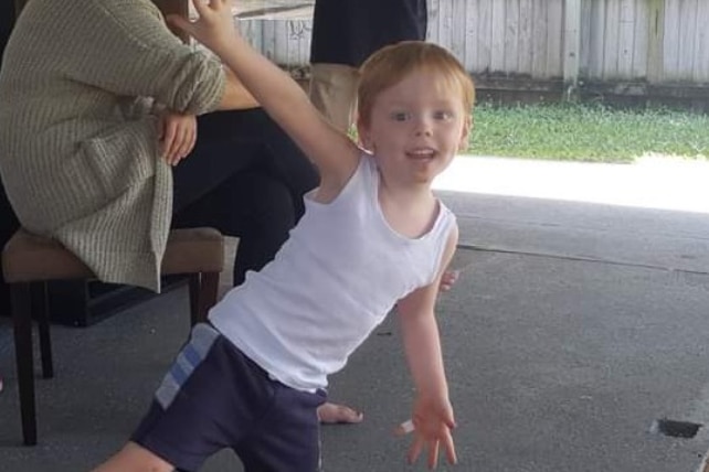 A young boy smiling on a patio