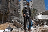 A young Arab man stands in the rubble of a blown apart building