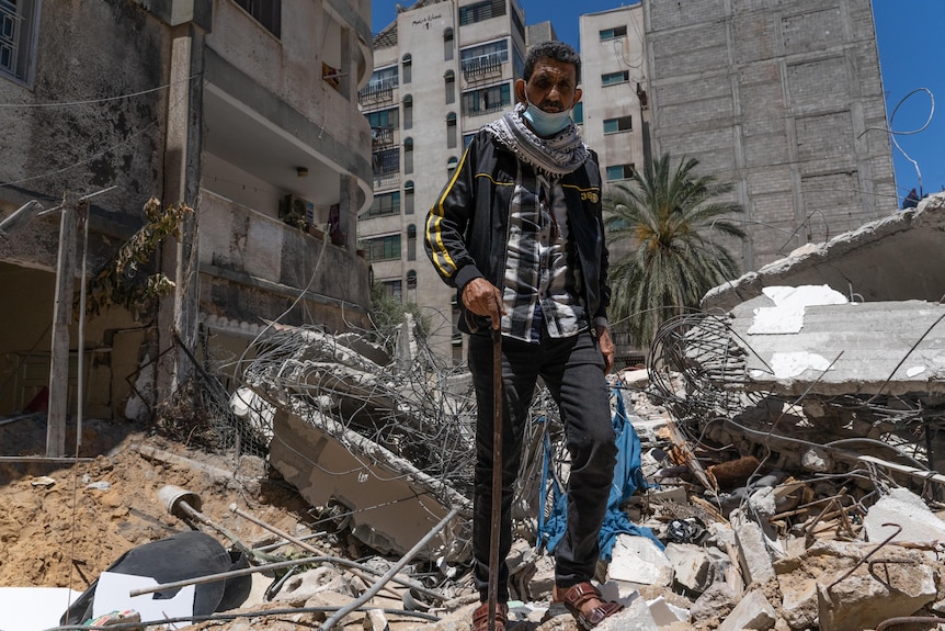 A young Arab man stands in the rubble of a blown apart building